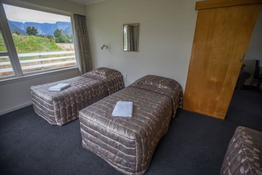 Cottage bedroom with 3 single beds and a view of Fox Glacier township